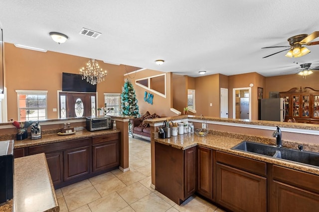 kitchen featuring a textured ceiling, stainless steel fridge, light tile patterned floors, and sink