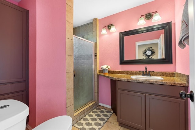 bathroom featuring tile patterned flooring, vanity, toilet, and a shower with shower door