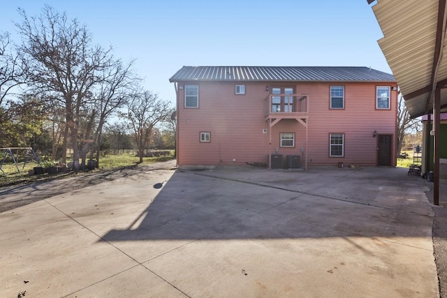 rear view of property featuring a balcony and central AC unit