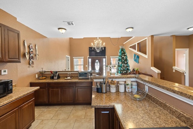 455 High View Ranch Dr, Cedar Creek, TX 78612 - kitchen featuring black microwave, a chandelier, light tile patterned flooring, a textured ceiling, and a peninsula