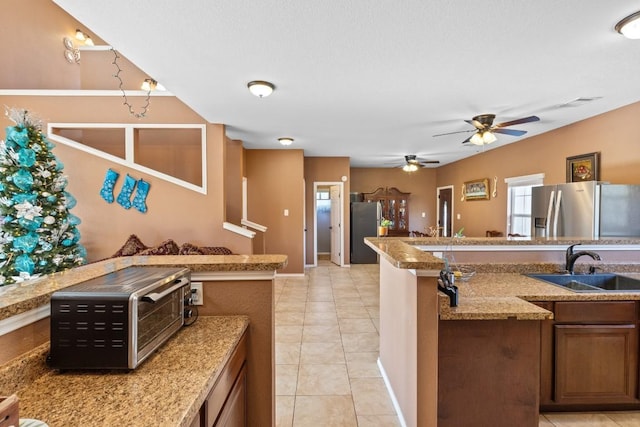 kitchen with sink, stainless steel fridge, light stone countertops, light tile patterned floors, and stainless steel fridge with ice dispenser