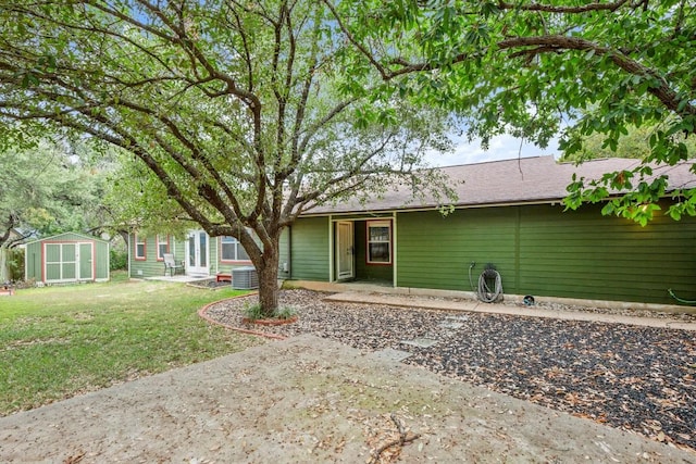 rear view of house with central air condition unit, a yard, a patio, and a storage shed