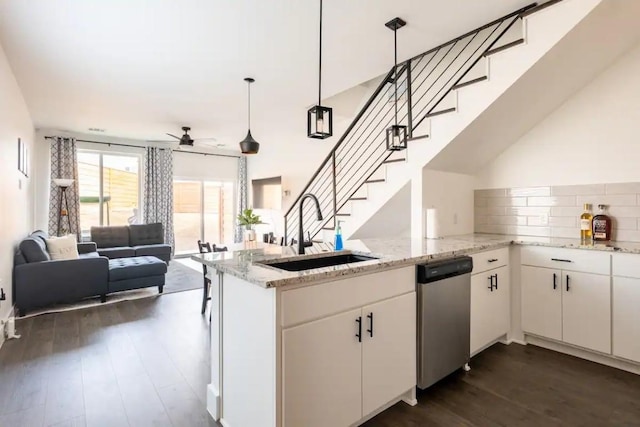 kitchen featuring kitchen peninsula, sink, white cabinets, and decorative light fixtures