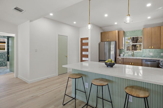 kitchen with hanging light fixtures, light stone counters, a breakfast bar, and stainless steel appliances