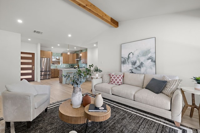 living room featuring vaulted ceiling with beams and light hardwood / wood-style flooring