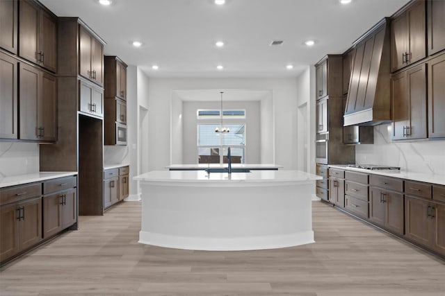 kitchen with appliances with stainless steel finishes, dark brown cabinetry, and decorative light fixtures