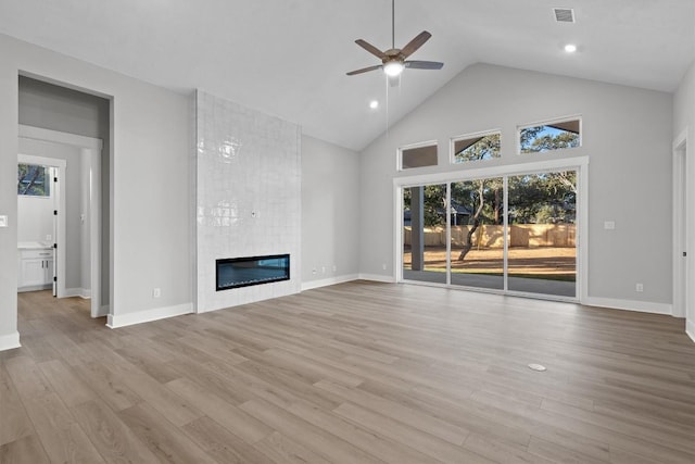 unfurnished living room featuring ceiling fan, light hardwood / wood-style floors, a fireplace, and high vaulted ceiling