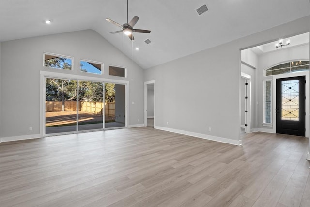 unfurnished living room featuring ceiling fan with notable chandelier, light hardwood / wood-style floors, and high vaulted ceiling