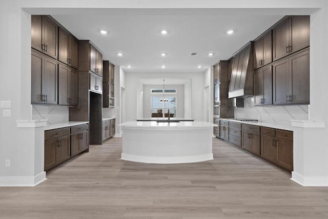 kitchen with decorative backsplash, dark brown cabinets, light wood-type flooring, and appliances with stainless steel finishes