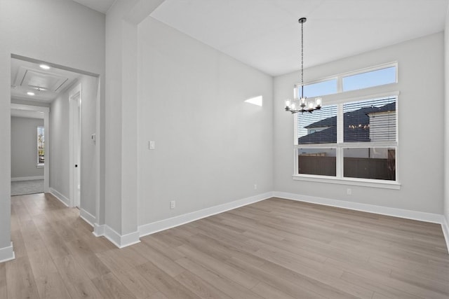 unfurnished dining area featuring a chandelier, light wood-type flooring, and plenty of natural light