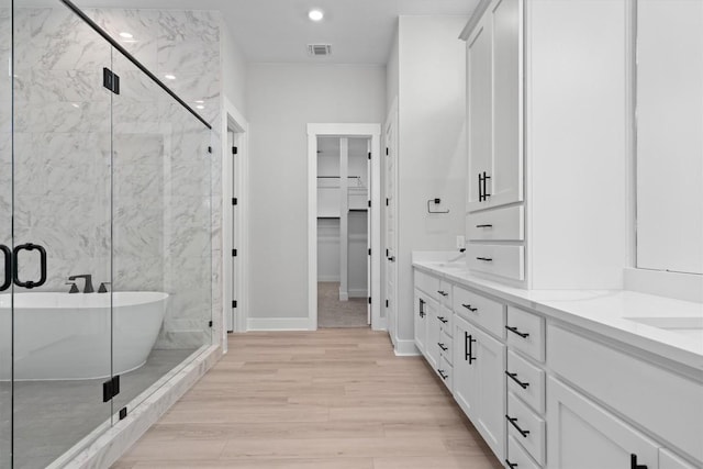 bathroom with plus walk in shower, hardwood / wood-style floors, and vanity