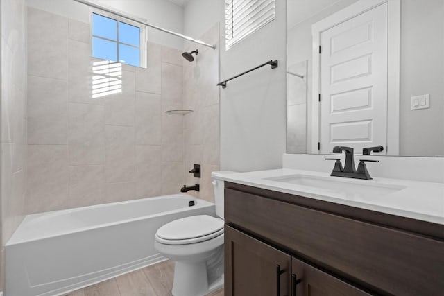 full bathroom with tiled shower / bath, vanity, a healthy amount of sunlight, and hardwood / wood-style flooring