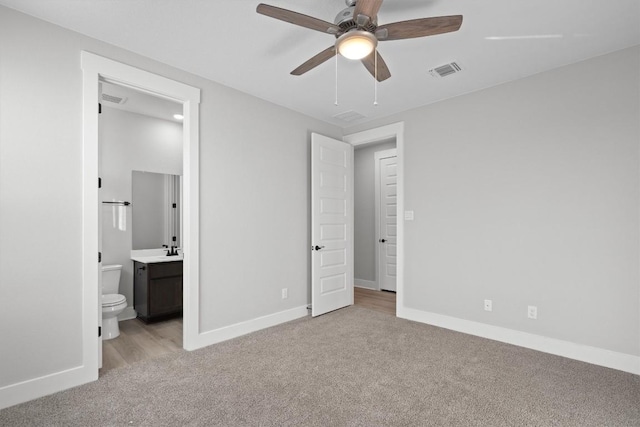 unfurnished bedroom featuring ensuite bathroom, ceiling fan, light colored carpet, and sink