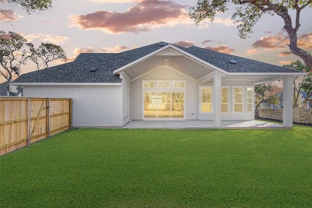 back house at dusk with a yard and a patio