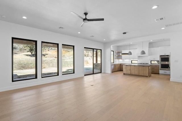 unfurnished living room with ceiling fan, plenty of natural light, and light hardwood / wood-style flooring