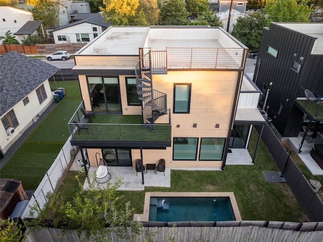 back of property featuring a yard, a balcony, a fenced in pool, and a patio area