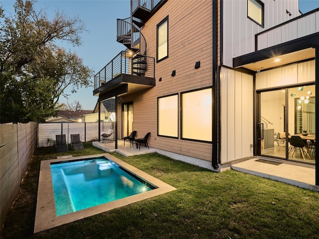 exterior space featuring a balcony, central air condition unit, a patio, a fenced in pool, and a lawn