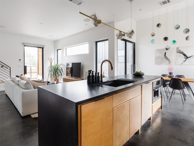 kitchen with sink, oven, pendant lighting, a kitchen island with sink, and light brown cabinetry