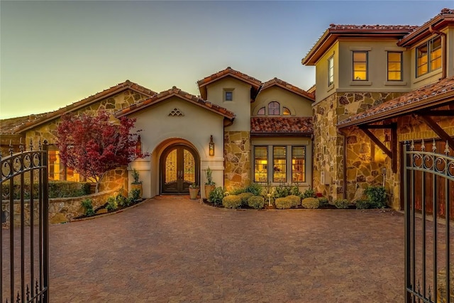 403 Rough Hollow Cv, Austin, TX 78734 - mediterranean / spanish-style home with french doors, stone siding, stucco siding, a tile roof, and a gate