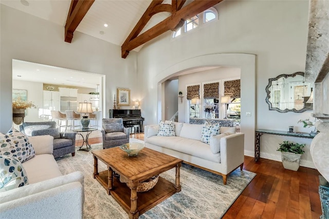 living area featuring dark wood-style floors, arched walkways, high vaulted ceiling, beamed ceiling, and baseboards