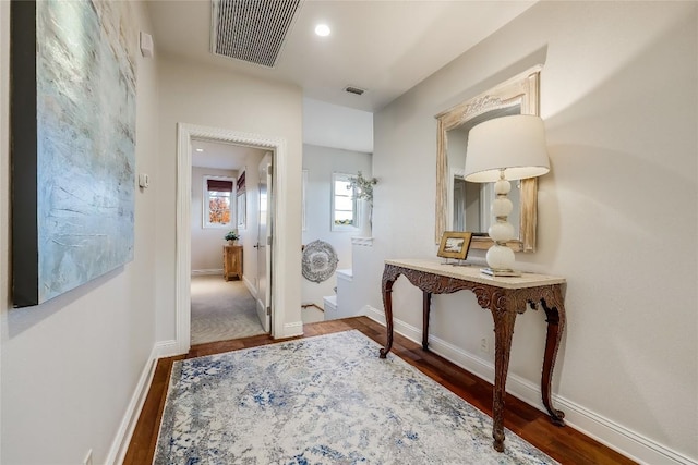 corridor featuring baseboards, visible vents, and dark wood-type flooring