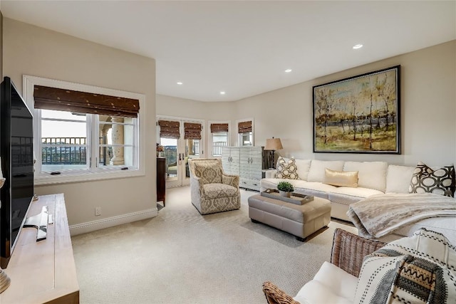 living area featuring baseboards, recessed lighting, light colored carpet, and a healthy amount of sunlight