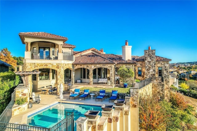 403 Rough Hollow Cv, Austin, TX 78734 - rear view of house with a balcony, a tiled roof, stone siding, a patio, and a chimney
