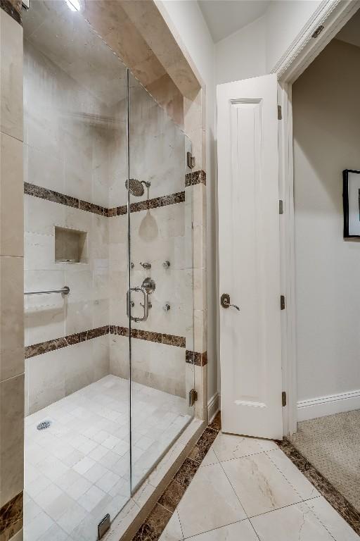 full bath featuring a shower stall and baseboards