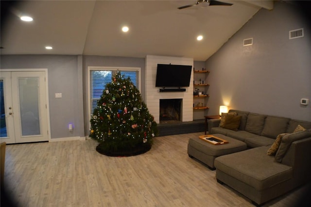 living room featuring french doors, lofted ceiling with beams, ceiling fan, light wood-type flooring, and a fireplace