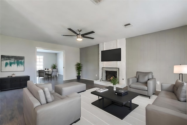 living room featuring ceiling fan, a fireplace, and light wood-type flooring