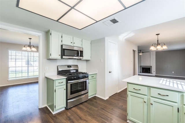 kitchen with an inviting chandelier, stainless steel appliances, a fireplace, and green cabinets