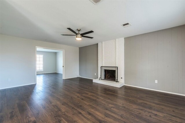 unfurnished living room featuring a brick fireplace, dark hardwood / wood-style floors, and ceiling fan