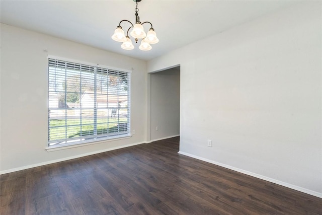 spare room featuring an inviting chandelier and dark hardwood / wood-style floors