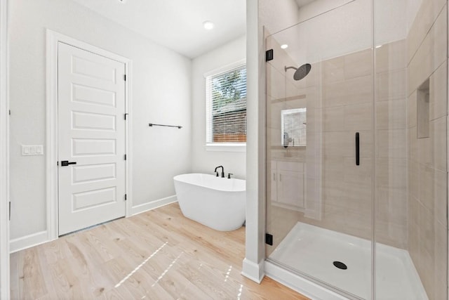 bathroom featuring shower with separate bathtub and wood-type flooring