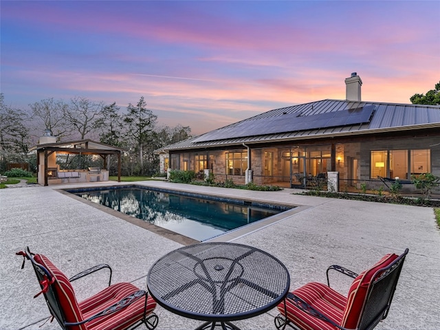 pool at dusk featuring a gazebo and a patio