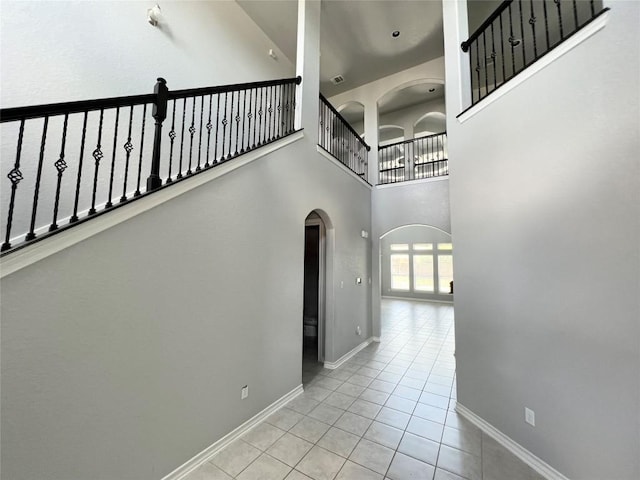 hall featuring light tile patterned floors and a towering ceiling