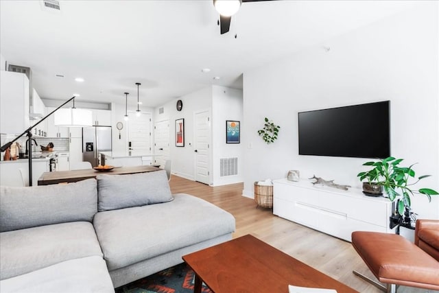 living room featuring light wood-type flooring and ceiling fan