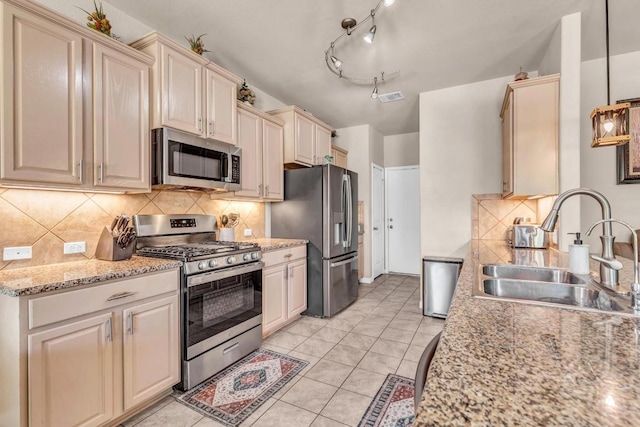 kitchen with light stone countertops, sink, decorative light fixtures, and appliances with stainless steel finishes