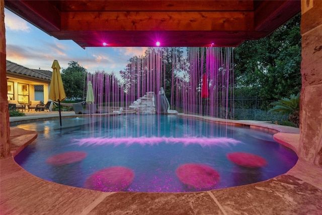 pool at dusk with a patio area