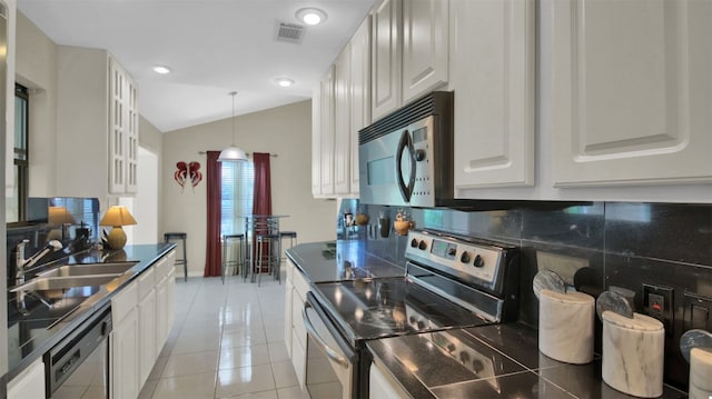 kitchen with lofted ceiling, sink, light tile patterned floors, white cabinetry, and stainless steel appliances