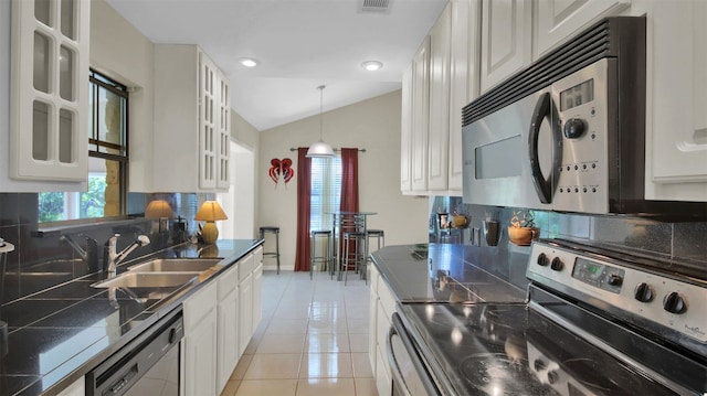 kitchen featuring white cabinets, appliances with stainless steel finishes, lofted ceiling, and sink