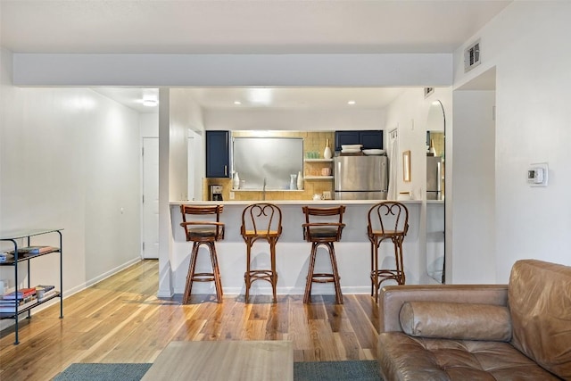 kitchen with visible vents, blue cabinetry, fridge, and freestanding refrigerator