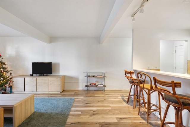 interior space with light wood finished floors, track lighting, baseboards, and beamed ceiling