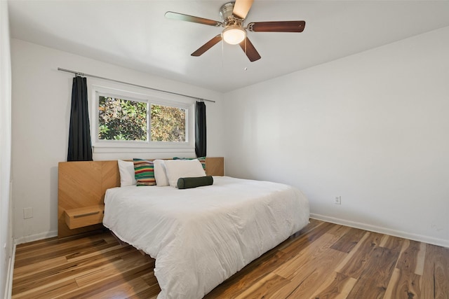 bedroom featuring ceiling fan, baseboards, and wood finished floors