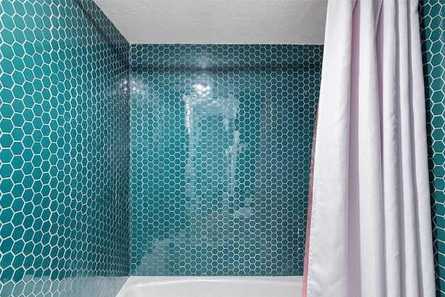 full bathroom with a tile shower and a textured ceiling