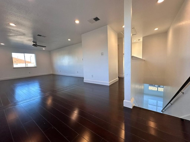 unfurnished room with a textured ceiling, ceiling fan, and dark wood-type flooring