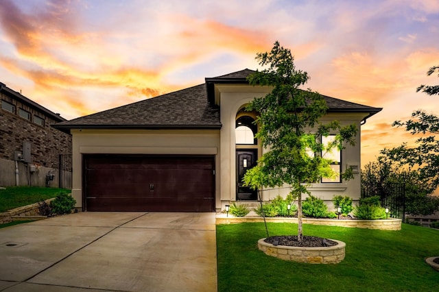 view of front of property featuring concrete driveway, an attached garage, a lawn, and stucco siding