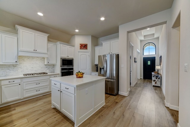 kitchen featuring light countertops, appliances with stainless steel finishes, white cabinetry, light wood-type flooring, and backsplash