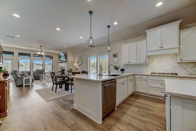 kitchen featuring stainless steel appliances, light wood finished floors, open floor plan, and light countertops