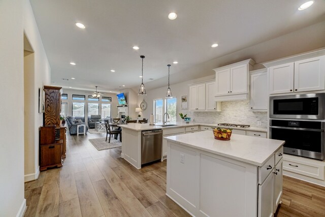 kitchen with a kitchen island, light wood-style flooring, light countertops, appliances with stainless steel finishes, and open floor plan